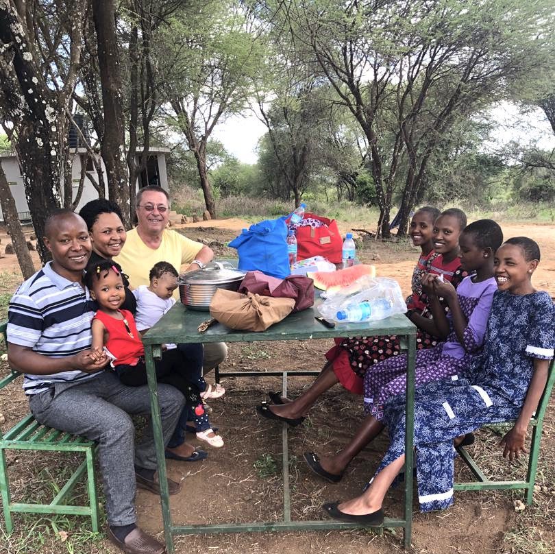 Elisante and his wife Nuruel, Rick, and MGRC students sitting at a picnic table after returning from safari trip in Tanzania.