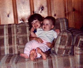 young girl sitting on a couch holding her baby sister on her lap