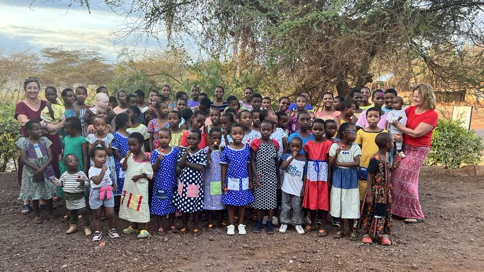 The girls showing off their new dresses from Threads of Hope, delivered by volunteer Cammy West.