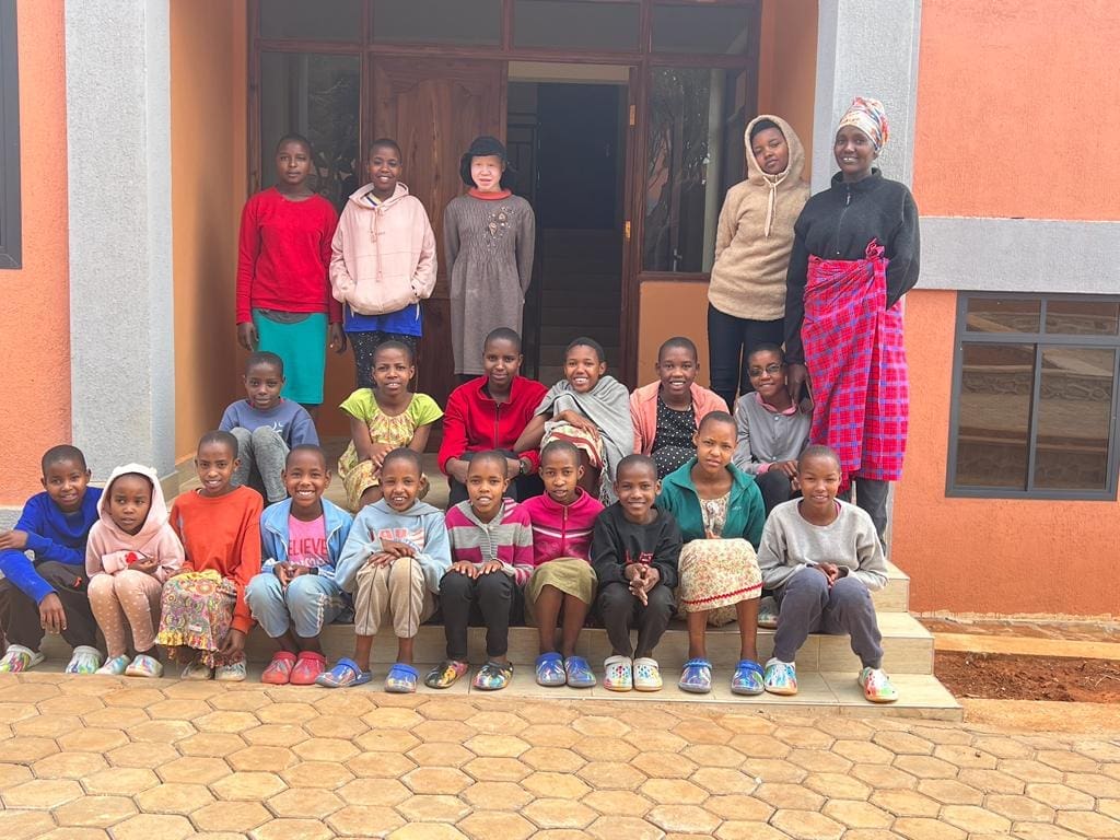 MGRC girls sitting outside their new home with their house mothers