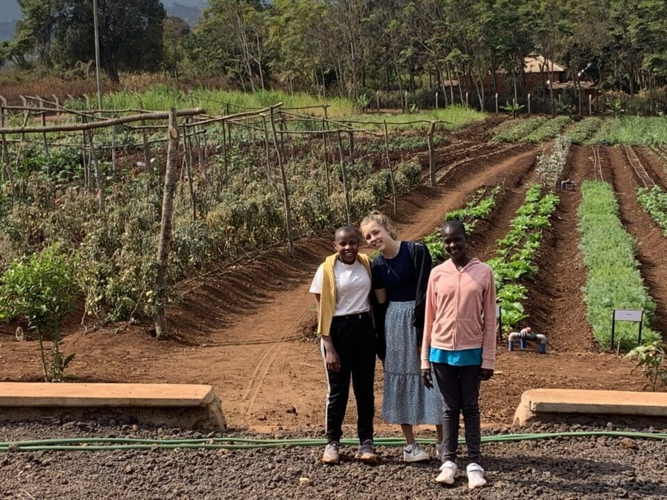 Young volunteer touring the ecoFarm with two Maasai girls