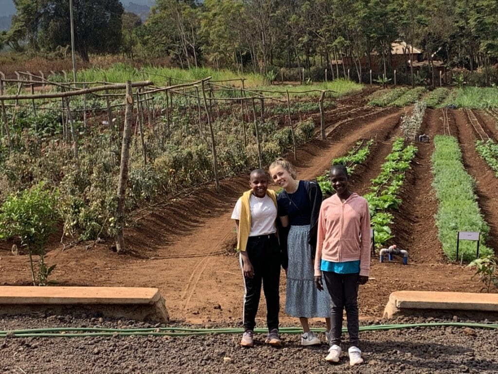 Young volunteer touring the ecoFarm with two Maasai girls