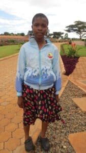 Mary standing outside the ecoVillage will begin her maasai education journey.