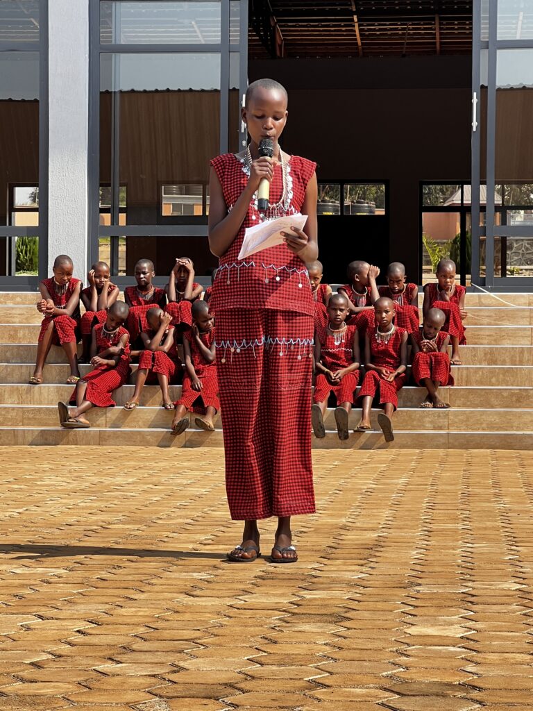 Namelock is reading the meaning of each color in the Maasai Shuka that the girls wear in the cultural performance.